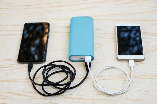 Two smartphones are charged using cables from the power bank