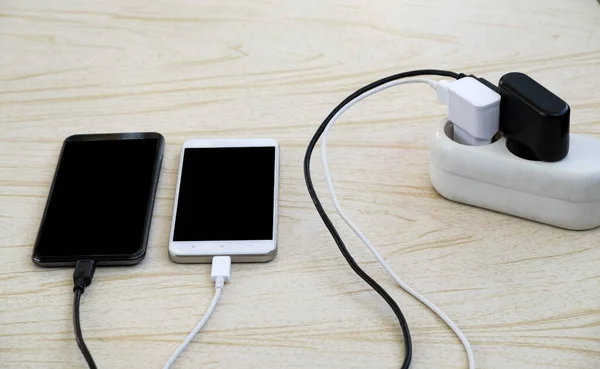 İki akıllı telefon bir elektrik prizinden kabloyla şarj edilir.