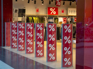 Alışveriş merkezinde indirim var. Mağazanın girişindeki kırmızı arkaplanda yüzde işareti