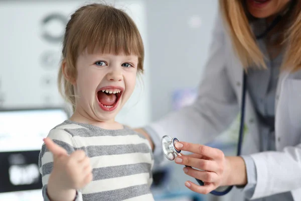 Симпатичная маленькая девочка в кабинете врача показывает — стоковое фото