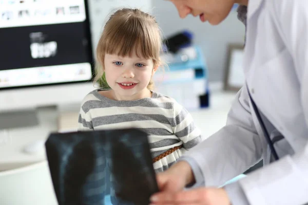 Vrouwelijke kinderarts werken met schattige kleine meisje op haar kantoor uitleggen diagnose Stockfoto