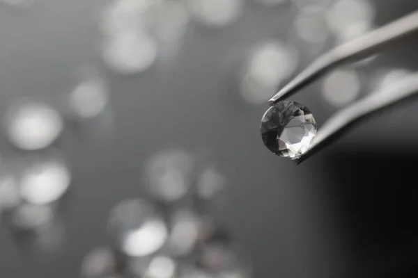 The jeweler holds a diamond in tweezers — Stock Photo, Image
