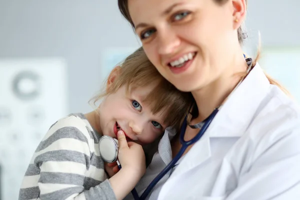 Kinderarzt hält und umarmt kleine süße Patientin — Stockfoto