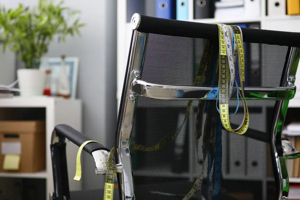 Measuring ribbons hanging on a black chair — Stock Photo, Image