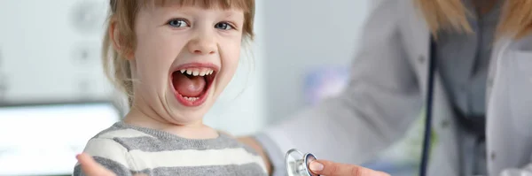 Cute Little Girl w gabinecie lekarza pokazując szacunek wdzięczność i zatwierdzić — Zdjęcie stockowe