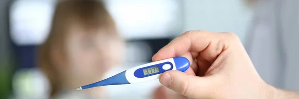 Male arm hold electronic thermometer showing high temperature at child doctor appointment