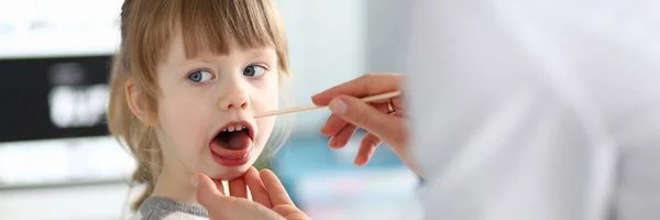 Kvinnlig pediatriker undersöka Little Kid patient halsen med träpinne — Stockfoto