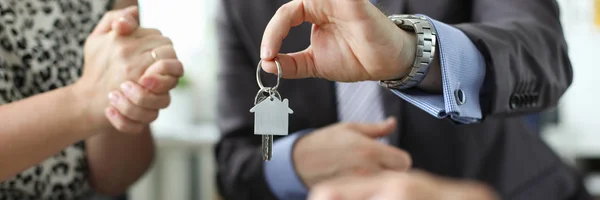 Hand of realtor hold house key aganist office Royalty Free Stock Photos