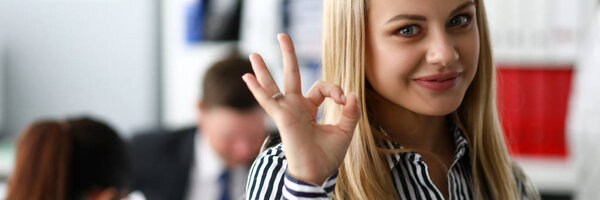 Smiling female clerk showing OK or confirm sign with her arm