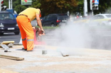 Erkek işçi elinde gaz kesiciyle betonu kesiyor..