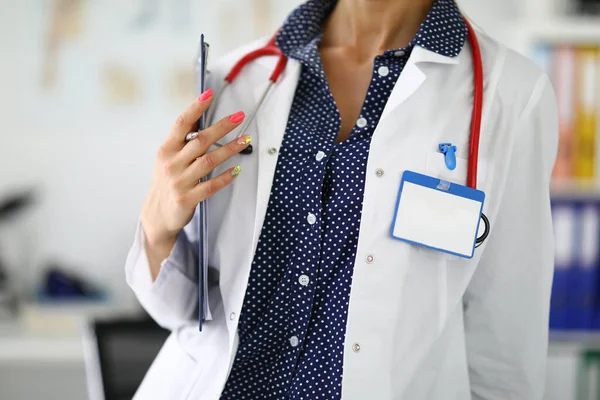 Ärztin mit Stethoskop hält Klemmbrett in den Händen. — Stockfoto