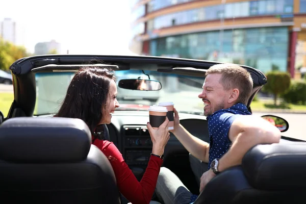 Mujer y hombre están bebiendo una bebida caliente en el coche y riendo . — Foto de Stock