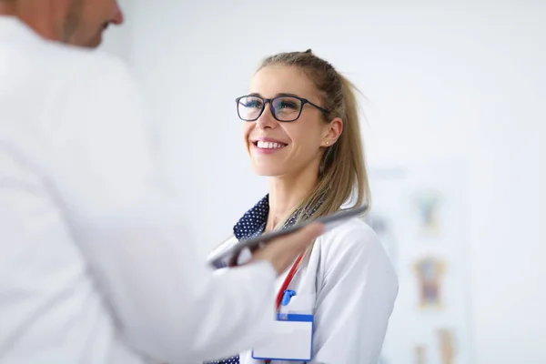 Γυναίκα γιατρός χαμογελά και επικοινωνεί με συνάδελφο. — Φωτογραφία Αρχείου