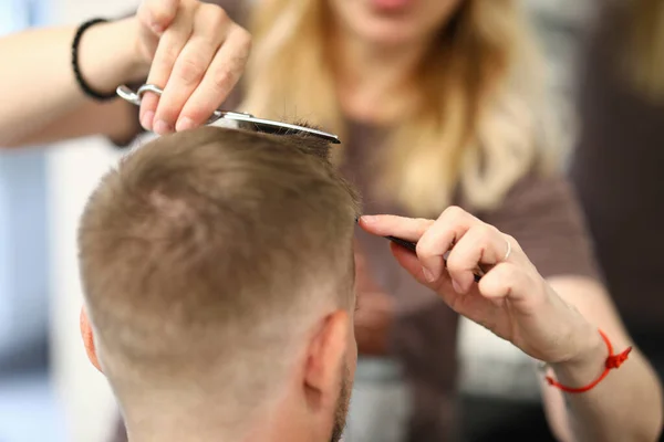 Woman hairdresser cuts mans hair in a beauty salon