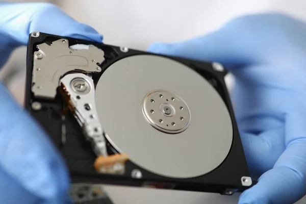 Gloved master holds hard drive away from computer.