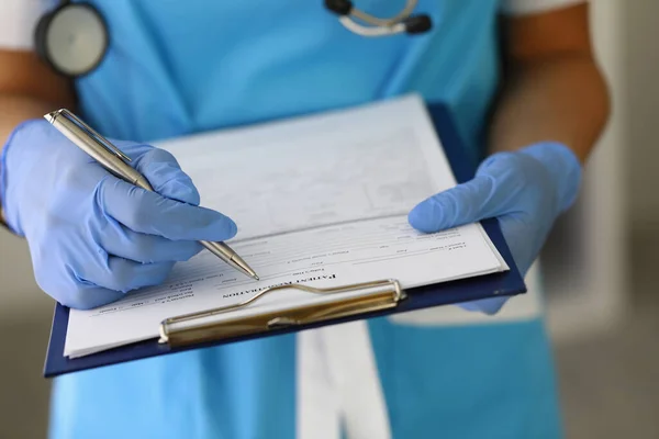 Ärzte mit Handschuhen halten Klemmbrett mit Stift und Patientenakte. — Stockfoto