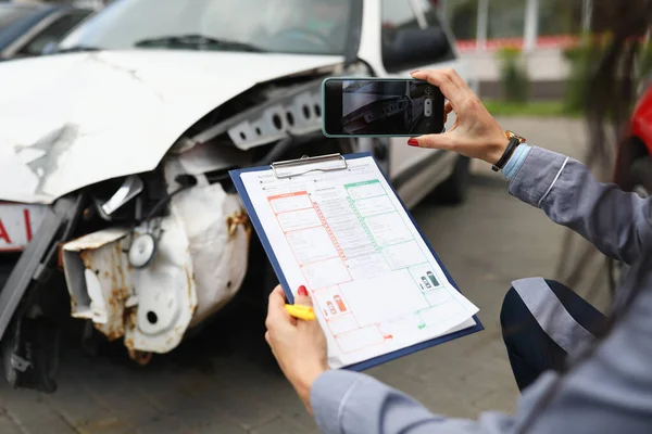 Agente de seguros toma fotos de coche estrellado en su teléfono inteligente y llena el seguro — Foto de Stock