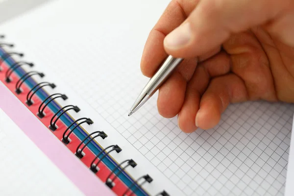 Mans hand holds pen on blank notebook