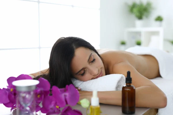 Woman lies with her eyes closed on massage table — Stock Photo, Image