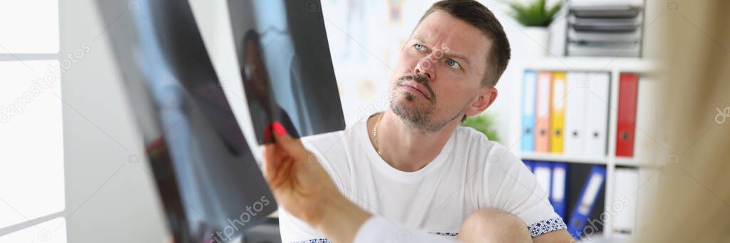 Man in medical office is looking at x-rays with doctor.