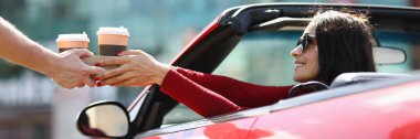 Cabriolet 'li kadın bir kuryeden sıcak içecek alıyor.