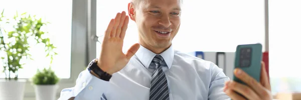 Empresario en la oficina hablando en videollamada en smartphone . — Foto de Stock