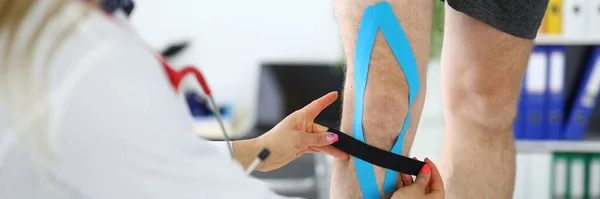 Dokter lijmt een elastische tape aan de benen van patiënten — Stockfoto