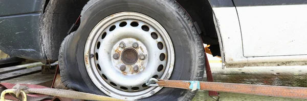 El coche está en la grúa con el primer plano pinchado del neumático — Foto de Stock