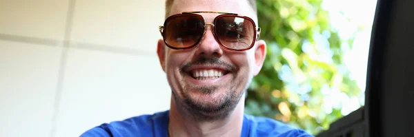 Man in sunglasses sits and smiles closeup — Stock Photo, Image