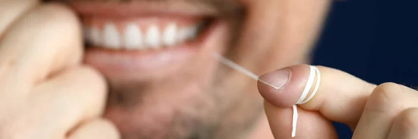 Usmívající se muž je čištění mezizubní prostor se zubní nit. — Stock fotografie