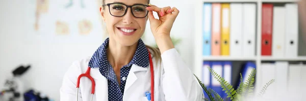 Mulher médico com óculos sorrindo no local de trabalho em consultório médico — Fotografia de Stock