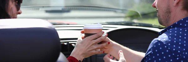 Hombre y mujer se sientan en el coche y sostienen el vaso de bebida juntos — Foto de Stock