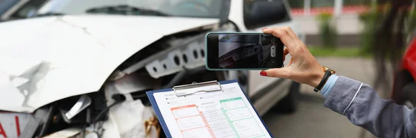 Försäkringsagent tar bilder av kraschade bil på sin smartphone och fyller i försäkringen — Stockfoto