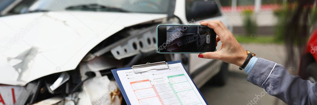 Insurance agent takes pictures of crashed car on his smartphone and fills out the insurance