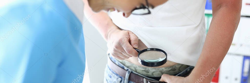 Patient holds magnifying glass over pants of medical worker smiling looks. — Stock Image Patient holds magnifying glass over pants of medical worker smiling looks. Stock Photo