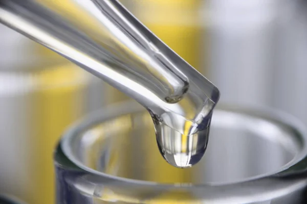 Chemická pipeta dávkovač kape žlutou kapalinu do skleněných detailů — Stock fotografie