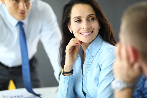 Jovem mulher de negócios em camisa azul se comunica com dois homens no escritório retrato — Fotografia de Stock