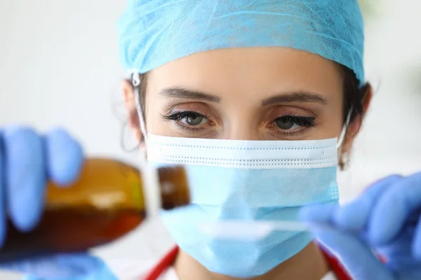 Kobieta lekarz w medycznej masce ochronnej wlewa lek ze słoika do łyżki portret — Zdjęcie stockowe