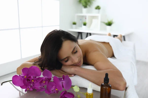 Young woman with closed eyes lies on couch in beauty salon — Stock Photo, Image