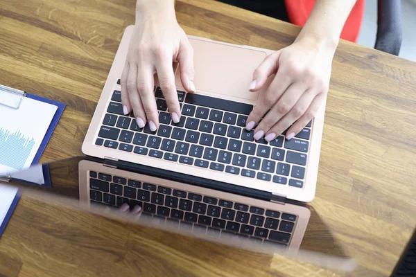 Женские руки печатают на клавиатуре ноутбука за столом в офисе крупным планом — стоковое фото