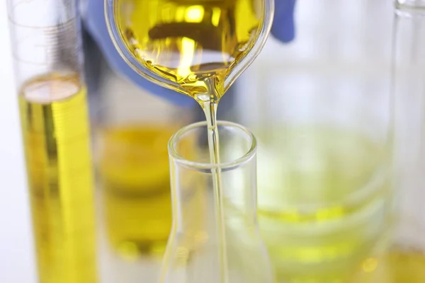 Vědci ruku v gumové rukavici nalévá žlutou kapalinu do skleněné zkumavky v chemické laboratoři detailní — Stock fotografie