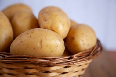 Beyaz arka plan üzerinde tekstil ile sepetiçinde patates yığını.