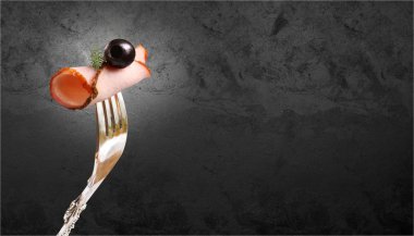 Zeytin ve siyah taş duvara karşı bir çatal üzerinde sabitlenmiş bir dereotu bir delikanlı ile füme et iştah açıcı parçası .