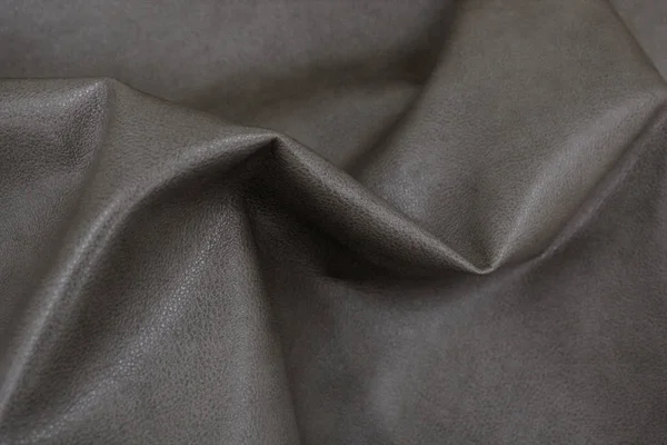 The texture of leather. The skin is laid in folds. Genuine leather for furniture. Gray leather.