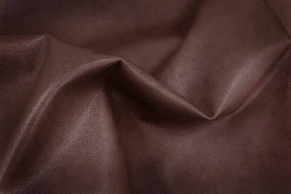 The texture of leather. The skin is laid in folds. Genuine leather for furniture. Red leather.