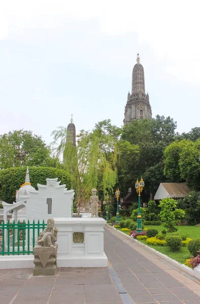 Wat Arun Ratchawararam or Temple of Dawn next to its gardens and some statues. — Stock Photo, Image