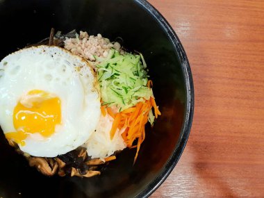 Kore gıda tarzı, Pirinç Top görünümü terbiyeli sebze ile tepesinde, et ve yan kadar kızarmış yumurta ahşap masada siyah bir kapta üstüne, Şablon metin için Alan, Bibimbap kore geleneksel