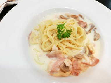 Beyaz tabakta krem soslu spagetti carbonara,beyaz tabakta pastırma ve mantarın üst görünümü, Şablondaki metin için boşluk. 