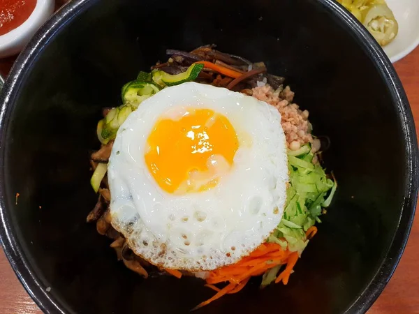 Kore gıda tarzı, Pirinç Top görünümü terbiyeli sebze ile tepesinde, et ve yan kadar kızarmış yumurta ahşap masada siyah bir kapta üstüne, Şablon metin için Alan, Bibimbap kore geleneksel