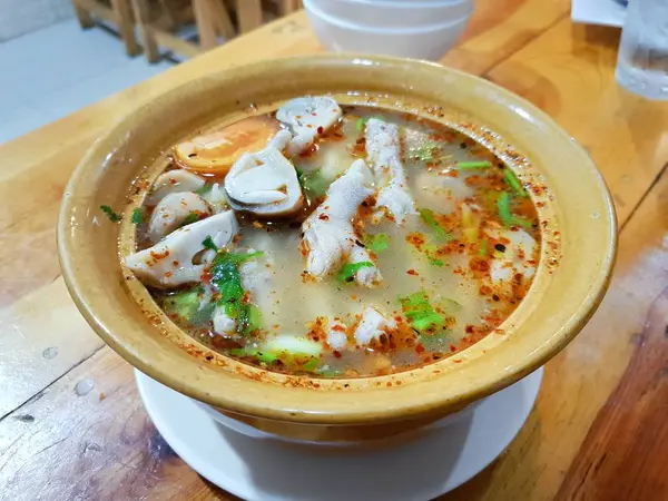 Tay gıda tarzı, Domates, mantar, biber ve kişniş ahşap masada sarı kase ile Tavuk Feet Baharatlı Çorba Closeup, Tom sab kha kai veya om yum süper Tay geleneksel 